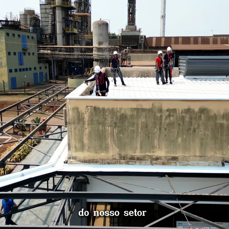 Trabalhadores parafusando telhas metálicas em cobertura industrial